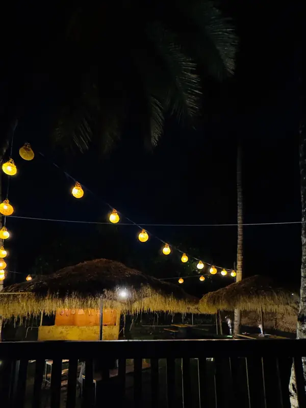 Festoon lights over the thatched cabanas, seen from the entrance