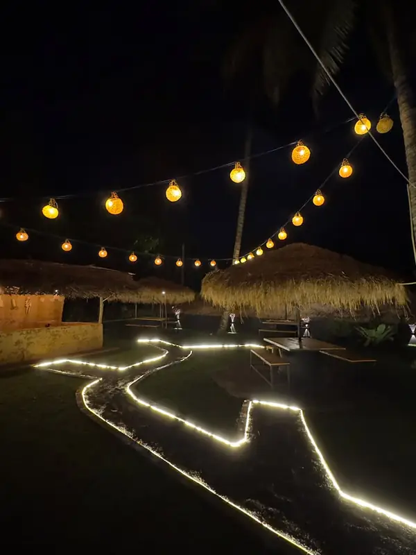 Cabanas and timber benches under a line of amber lights